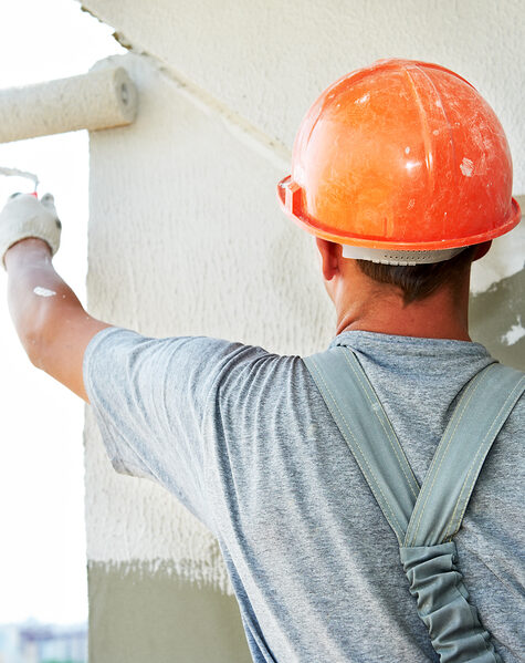 Young painting facade builder worker with roller at thermal insulation works