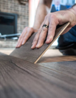 man installing engineered laminate wood floring indoor