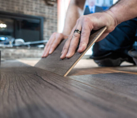 man installing engineered laminate wood floring indoor